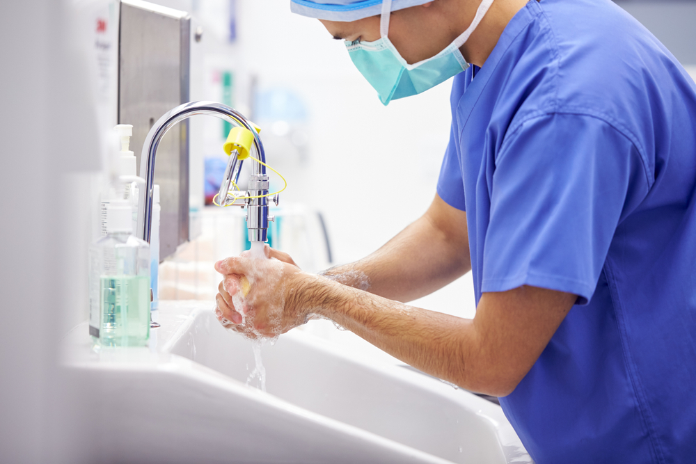 Male Surgeon Wearing Scrubs Washing Hands Before Operation In Hospital Operating Theater